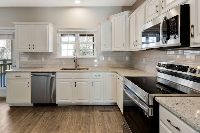 kitchen with sink, dark wood-type flooring, white cabinetry, stainless steel appliances, and light stone countertops