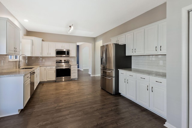 kitchen featuring sink, dark wood-type flooring, white cabinetry, stainless steel appliances, and light stone counters