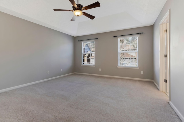 spare room featuring light carpet, a tray ceiling, and ceiling fan