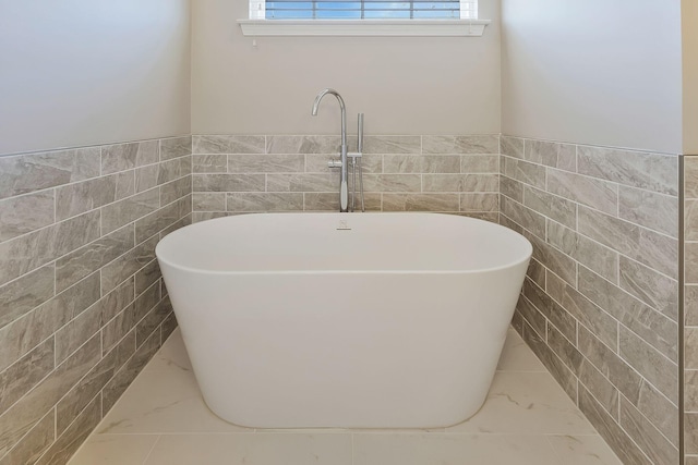 bathroom featuring a washtub and tile walls