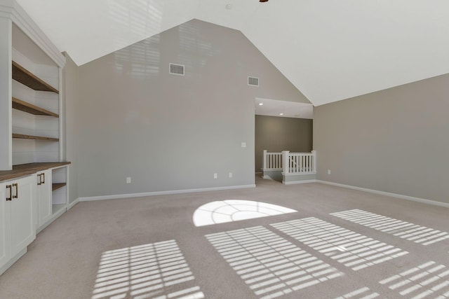 unfurnished living room featuring high vaulted ceiling and light colored carpet