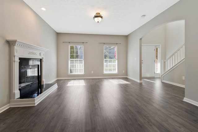 unfurnished living room featuring dark wood-type flooring and a textured ceiling