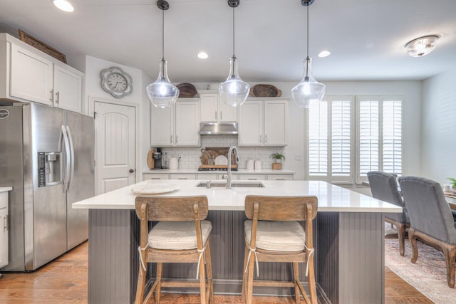 kitchen featuring stainless steel appliances, an island with sink, and pendant lighting