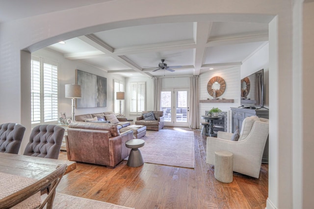 living room with ceiling fan, coffered ceiling, light hardwood / wood-style floors, and beam ceiling