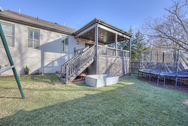 back of property featuring a yard and a trampoline