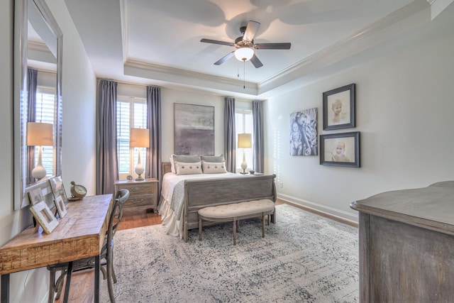 bedroom featuring crown molding, ceiling fan, wood-type flooring, and a raised ceiling