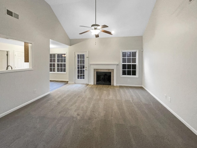 unfurnished living room featuring a tiled fireplace, carpet floors, high vaulted ceiling, and ceiling fan