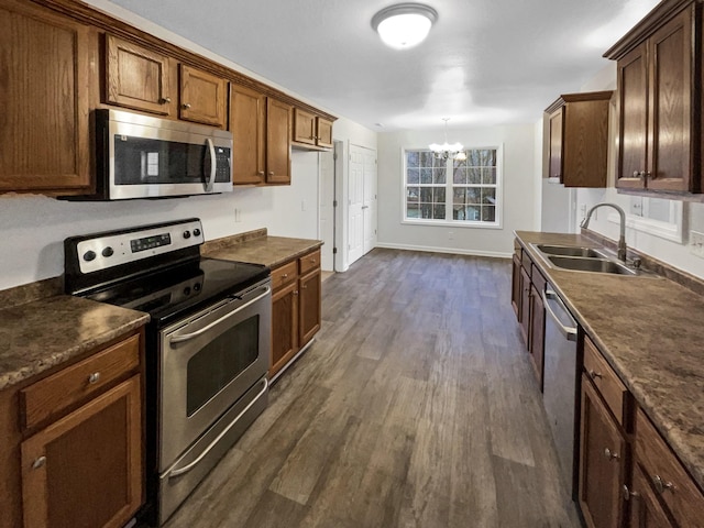 kitchen featuring dark wood-type flooring, sink, decorative light fixtures, appliances with stainless steel finishes, and a notable chandelier