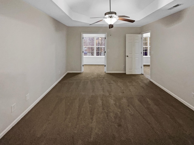 carpeted spare room with ceiling fan and a raised ceiling