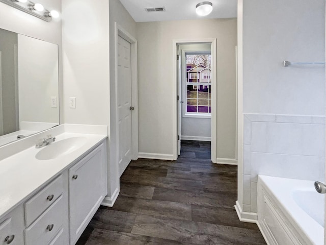 bathroom with a bath, vanity, and hardwood / wood-style floors