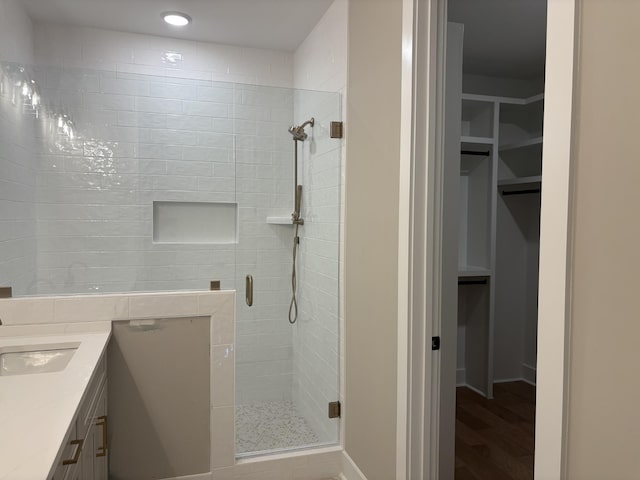 bathroom with a walk in closet, a shower stall, vanity, and recessed lighting