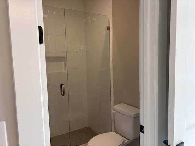 bathroom featuring toilet and a shower stall