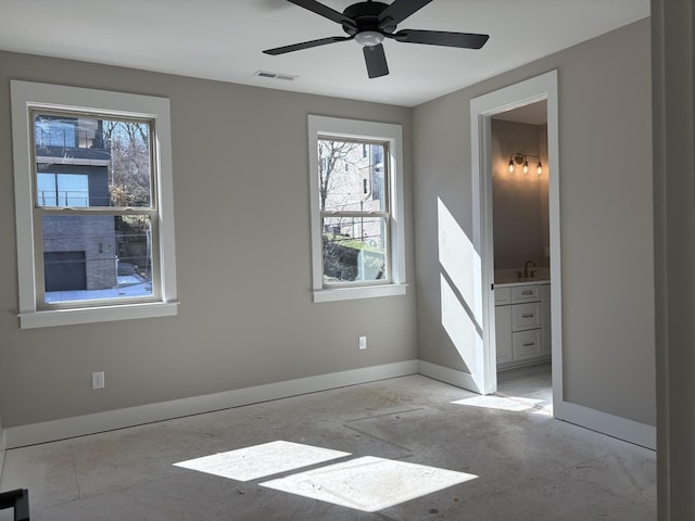 spare room featuring a ceiling fan, visible vents, a sink, and baseboards