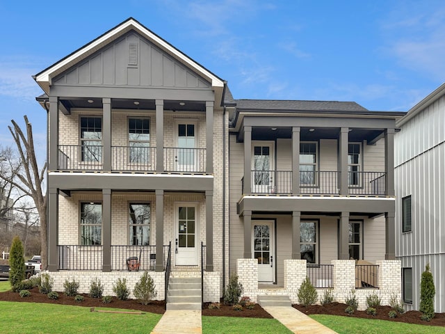 view of front of house featuring board and batten siding, covered porch, brick siding, and a balcony