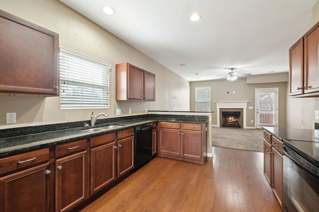 kitchen with range with electric cooktop, dishwasher, sink, a tiled fireplace, and light hardwood / wood-style floors