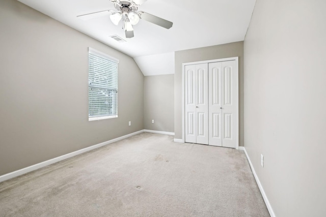 unfurnished bedroom with ceiling fan, light colored carpet, vaulted ceiling, and a closet