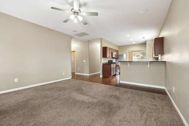 unfurnished living room featuring ceiling fan and dark carpet