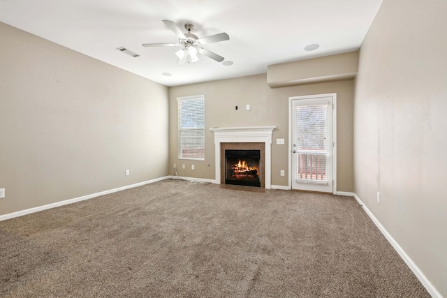 unfurnished living room with a tile fireplace, a healthy amount of sunlight, and carpet flooring