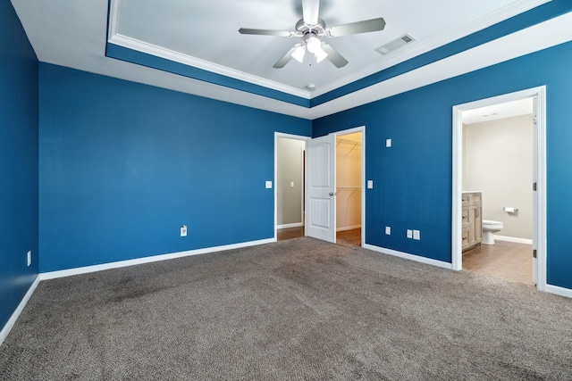 unfurnished bedroom featuring crown molding, a walk in closet, a closet, and carpet