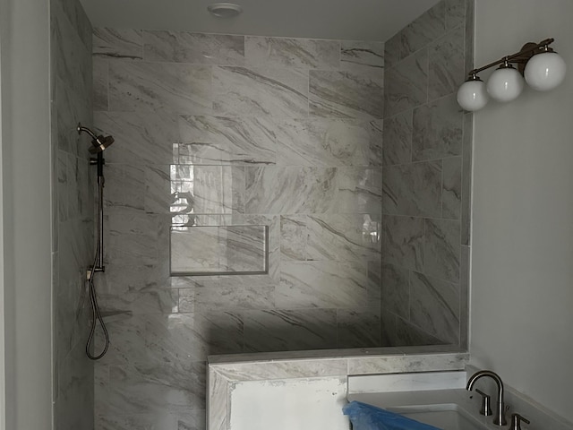 bathroom featuring a tile shower and sink