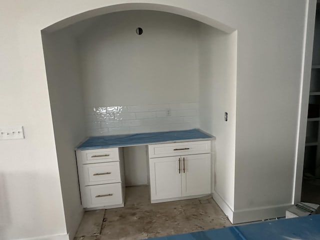 interior space featuring white cabinetry and unfinished concrete flooring