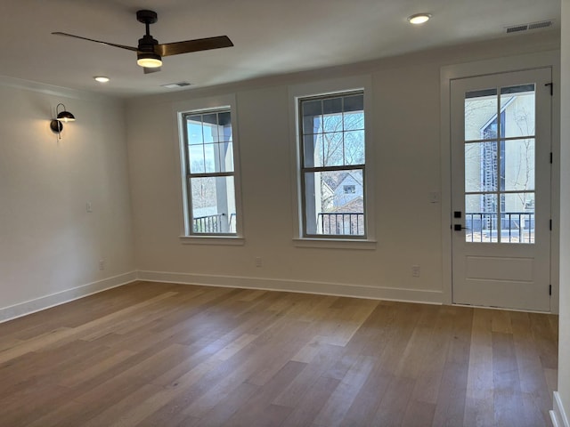 interior space featuring a ceiling fan, baseboards, visible vents, and wood finished floors