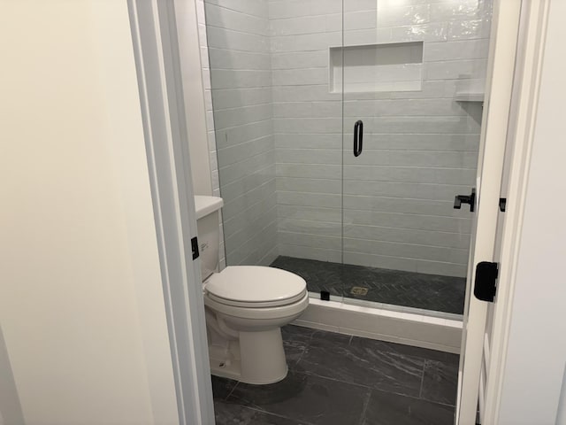 bathroom with marble finish floor, a shower stall, and toilet