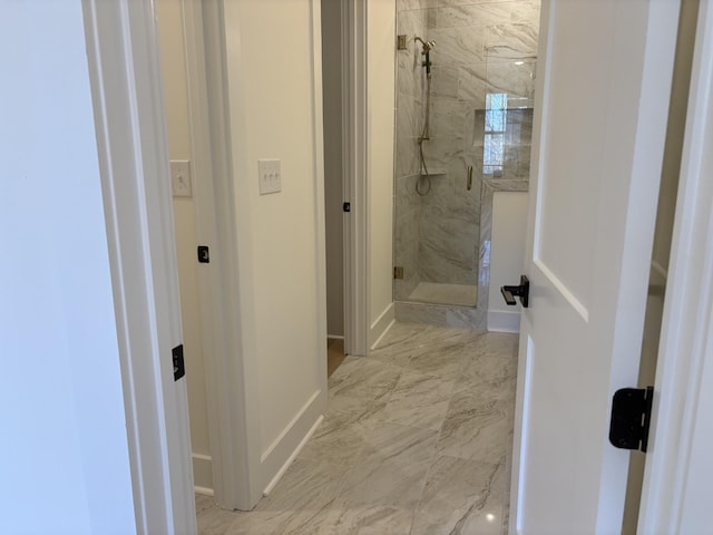 bathroom featuring marble finish floor, baseboards, and a marble finish shower