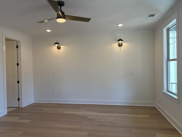 spare room featuring a healthy amount of sunlight, visible vents, light wood-style flooring, and baseboards