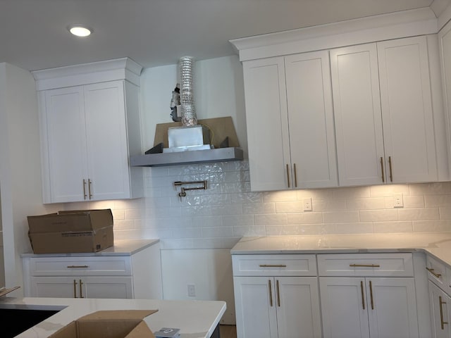 kitchen featuring light stone counters, white cabinetry, and backsplash