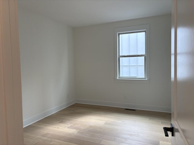 empty room featuring light wood-style floors, visible vents, and baseboards