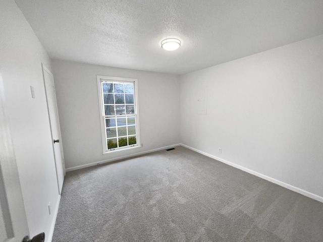 carpeted empty room featuring a textured ceiling