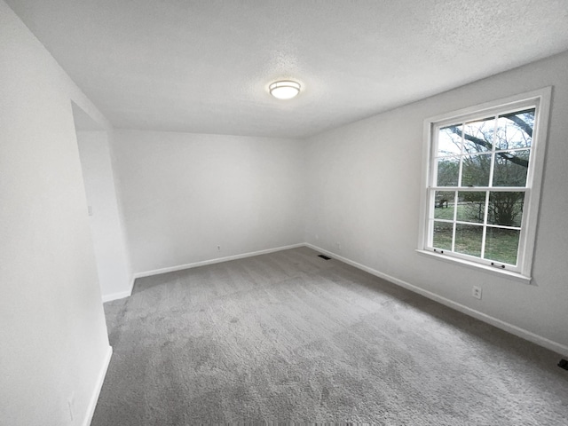 carpeted spare room with a textured ceiling