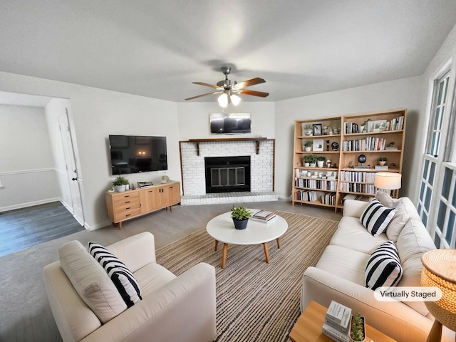 living room featuring ceiling fan, hardwood / wood-style floors, and a brick fireplace