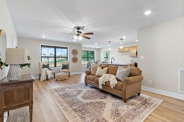 living room with sink, ceiling fan, and light wood-type flooring