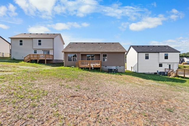 back of property with a deck, central air condition unit, and a lawn