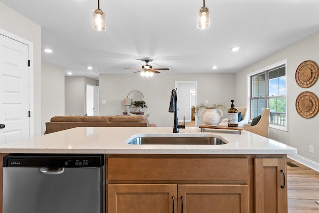 kitchen featuring pendant lighting, stainless steel dishwasher, light stone countertops, and sink