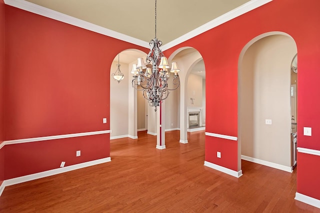 unfurnished dining area with wood-type flooring, ornamental molding, and a chandelier