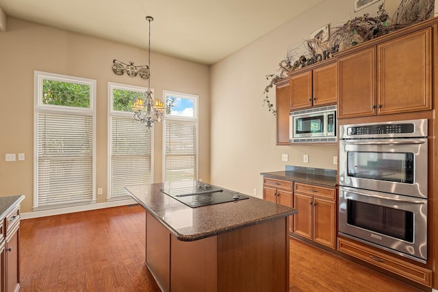 kitchen with an inviting chandelier, appliances with stainless steel finishes, dark hardwood / wood-style floors, and a center island