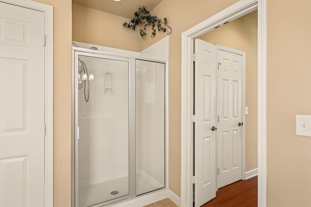 bathroom with a shower with shower door and hardwood / wood-style floors