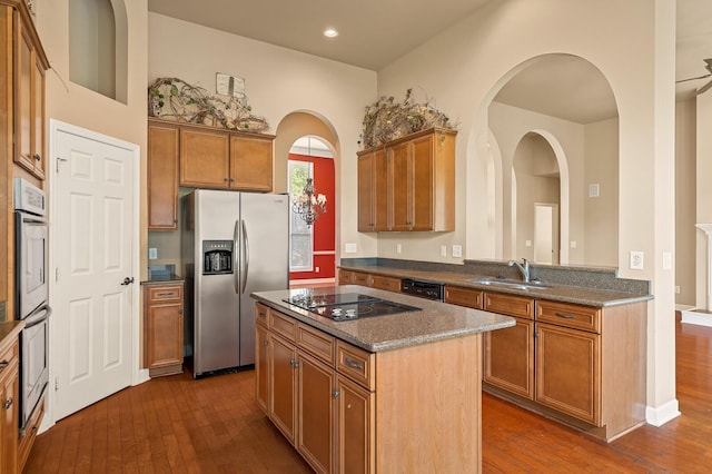 kitchen featuring dark hardwood / wood-style floors, sink, dark stone countertops, a center island, and black appliances