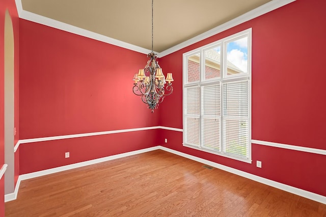 unfurnished room with crown molding, wood-type flooring, and a chandelier