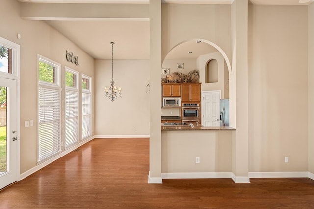 kitchen featuring pendant lighting, appliances with stainless steel finishes, dark hardwood / wood-style floors, and kitchen peninsula