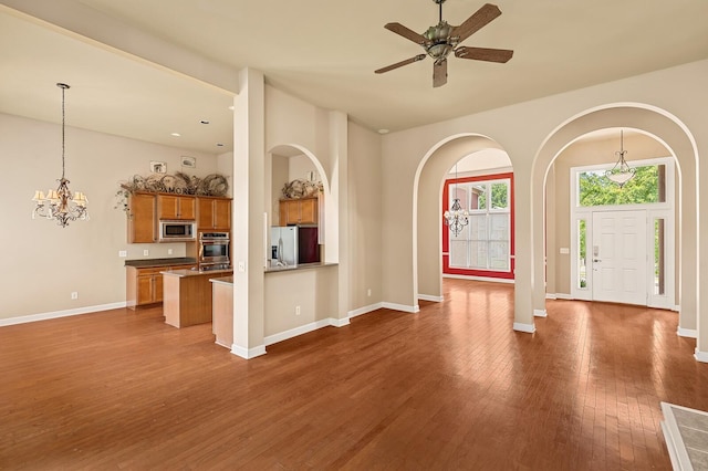 unfurnished living room with dark hardwood / wood-style flooring and ceiling fan with notable chandelier