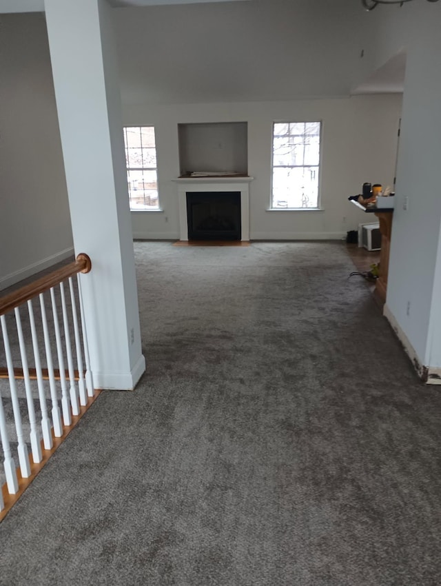 unfurnished living room featuring carpet, a fireplace, and baseboards