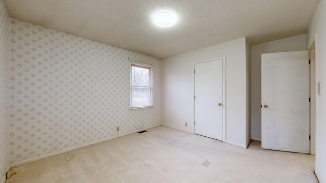 unfurnished bedroom featuring light carpet and a textured ceiling