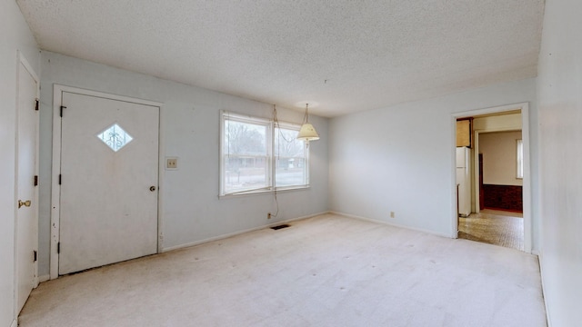 foyer featuring light carpet and a textured ceiling