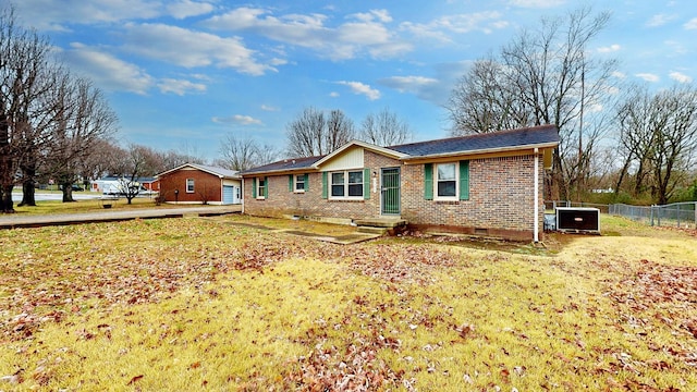 rear view of house with central AC unit and a yard