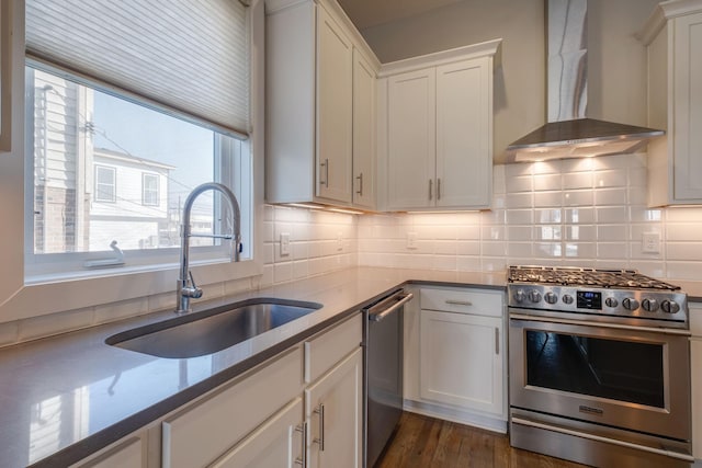 kitchen with wall chimney range hood, sink, appliances with stainless steel finishes, tasteful backsplash, and white cabinets