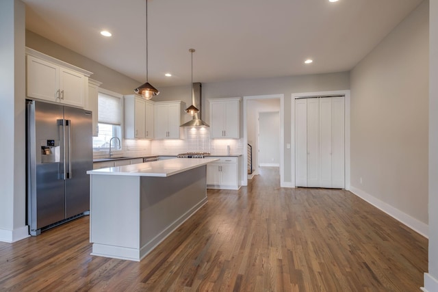 kitchen featuring wall chimney range hood, high quality fridge, a center island, and white cabinets